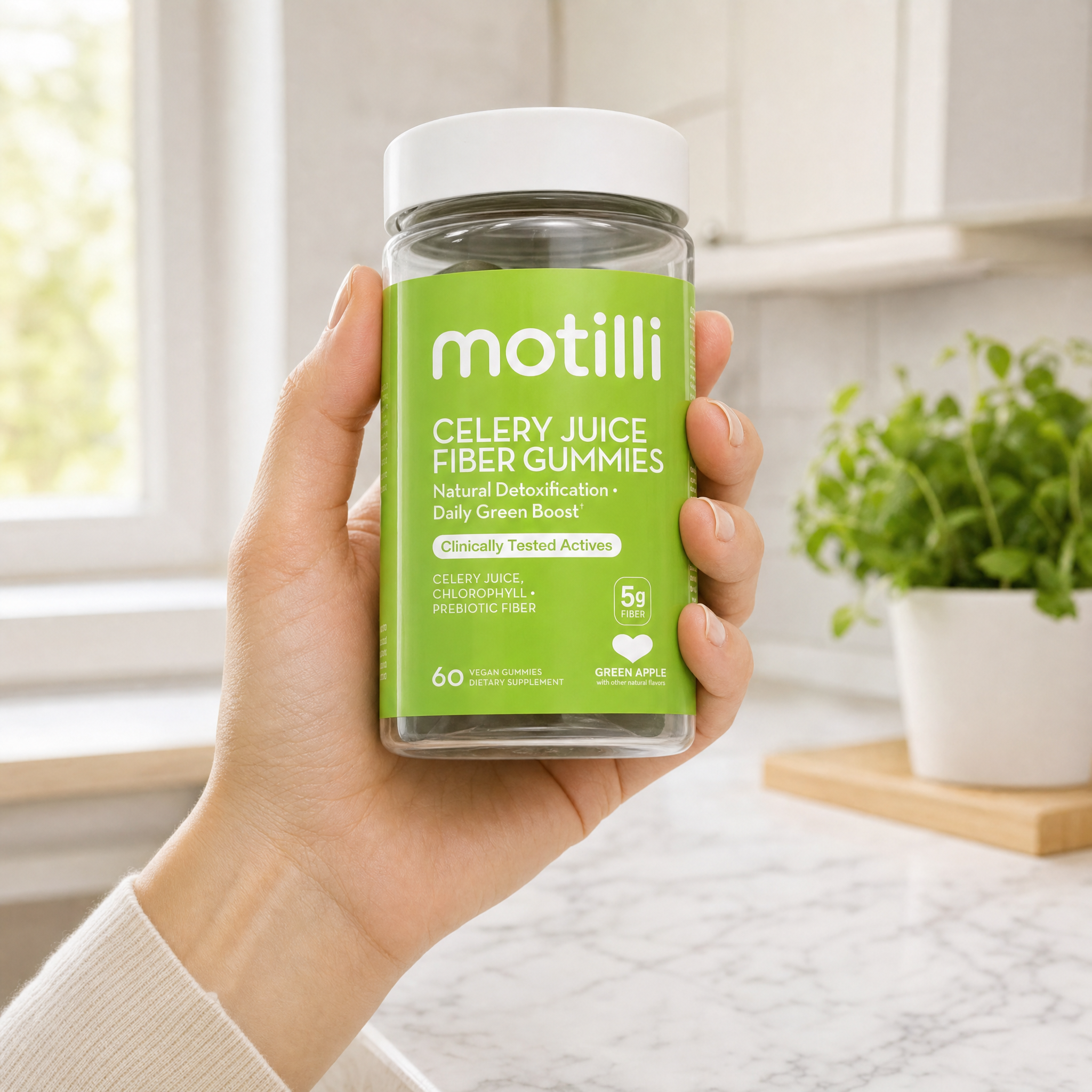Hand holding Motilli celery juice fiber gummies bottle in a clean kitchen